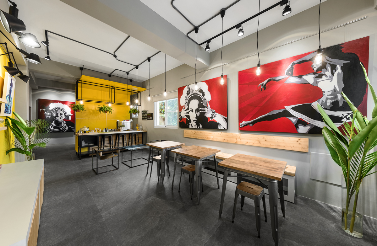 店面空間設計側拍：餐桌旁以紅、黑、灰、白為主色的原民主題繪畫，凸顯咖啡廳想表現的當地文化底蘊。