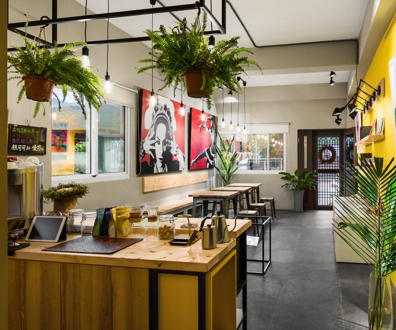 由櫃檯視角展開的店內空間：木製桌面配合綠色植物的點綴，舒緩平衡店內的強烈風格。