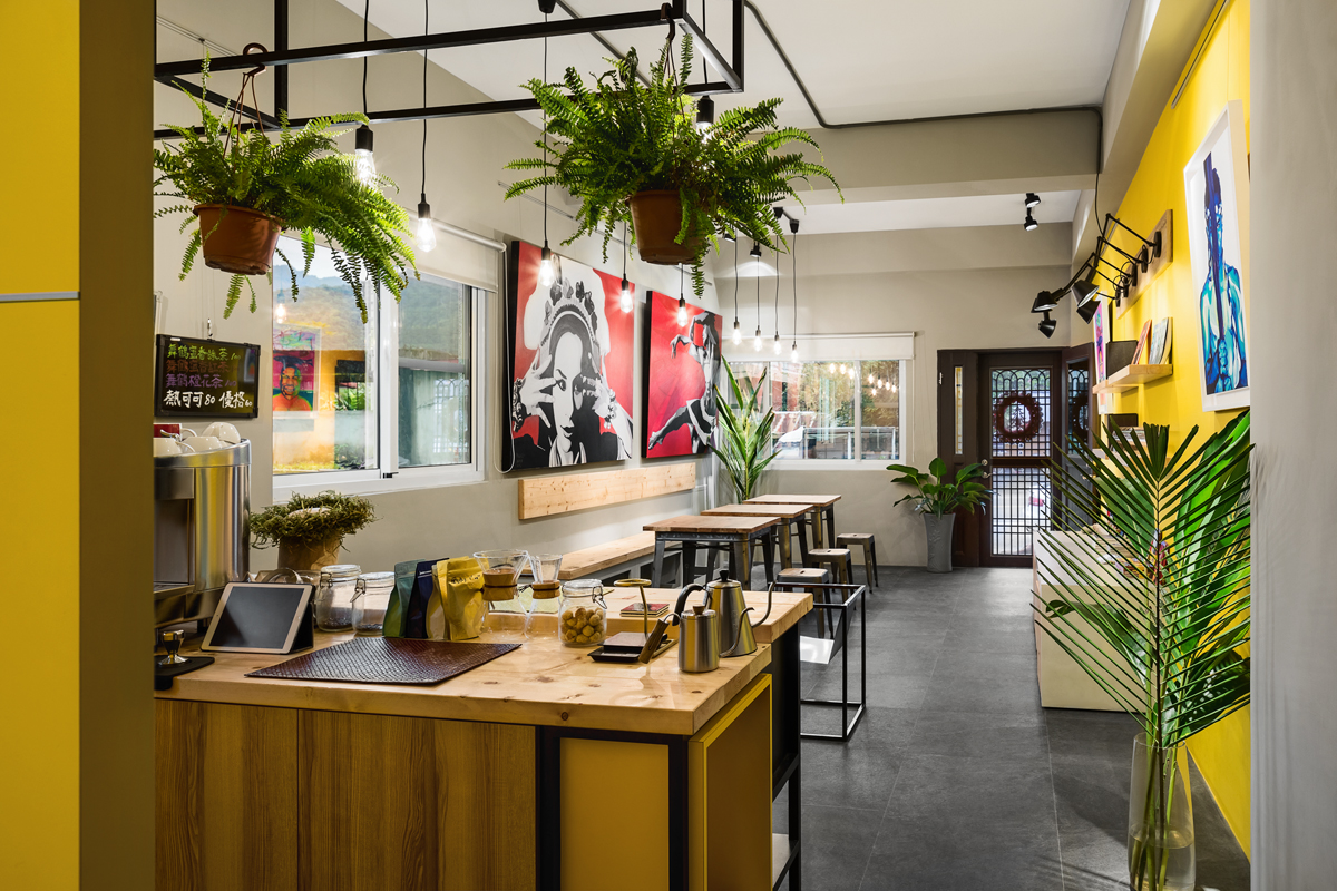 由櫃檯視角展開的店內空間：木製桌面配合綠色植物的點綴，舒緩平衡店內的強烈風格。